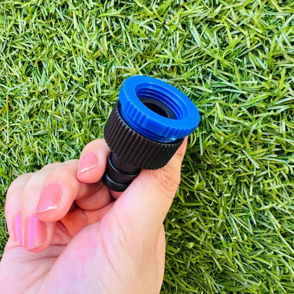 Hand holding the Expandable Magic Hose's blue tap connector fitting on grass